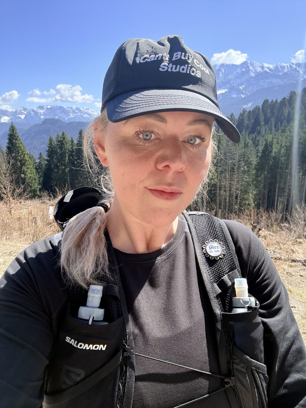 Ann-Kathrin Weitz mit Cap und Laufweste vor schneebedeckten Alpengipfeln